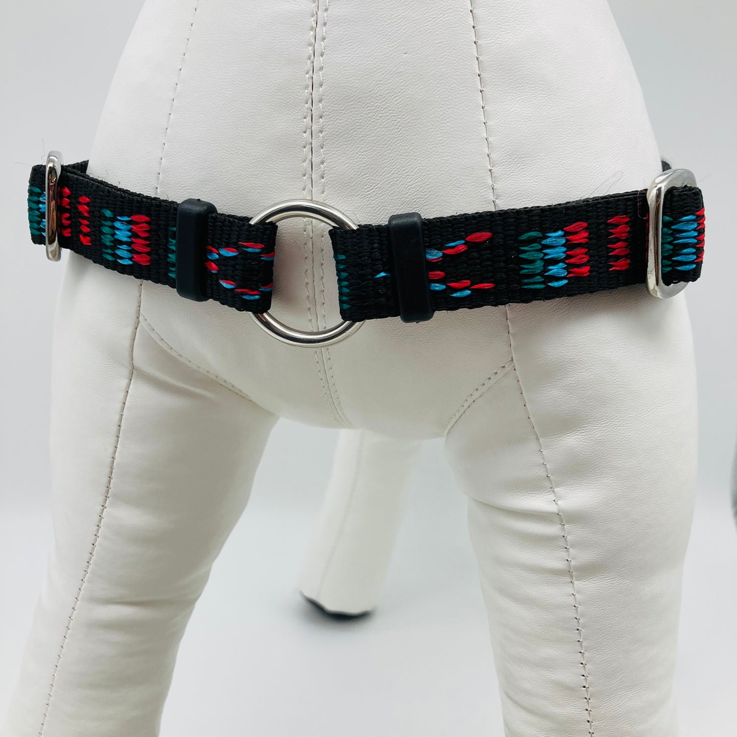 black Stitch (black fabric with print in 3 colors, red, light blue and green) harness, showing the chest from the front, the stainless steel ring where the leash is attached to