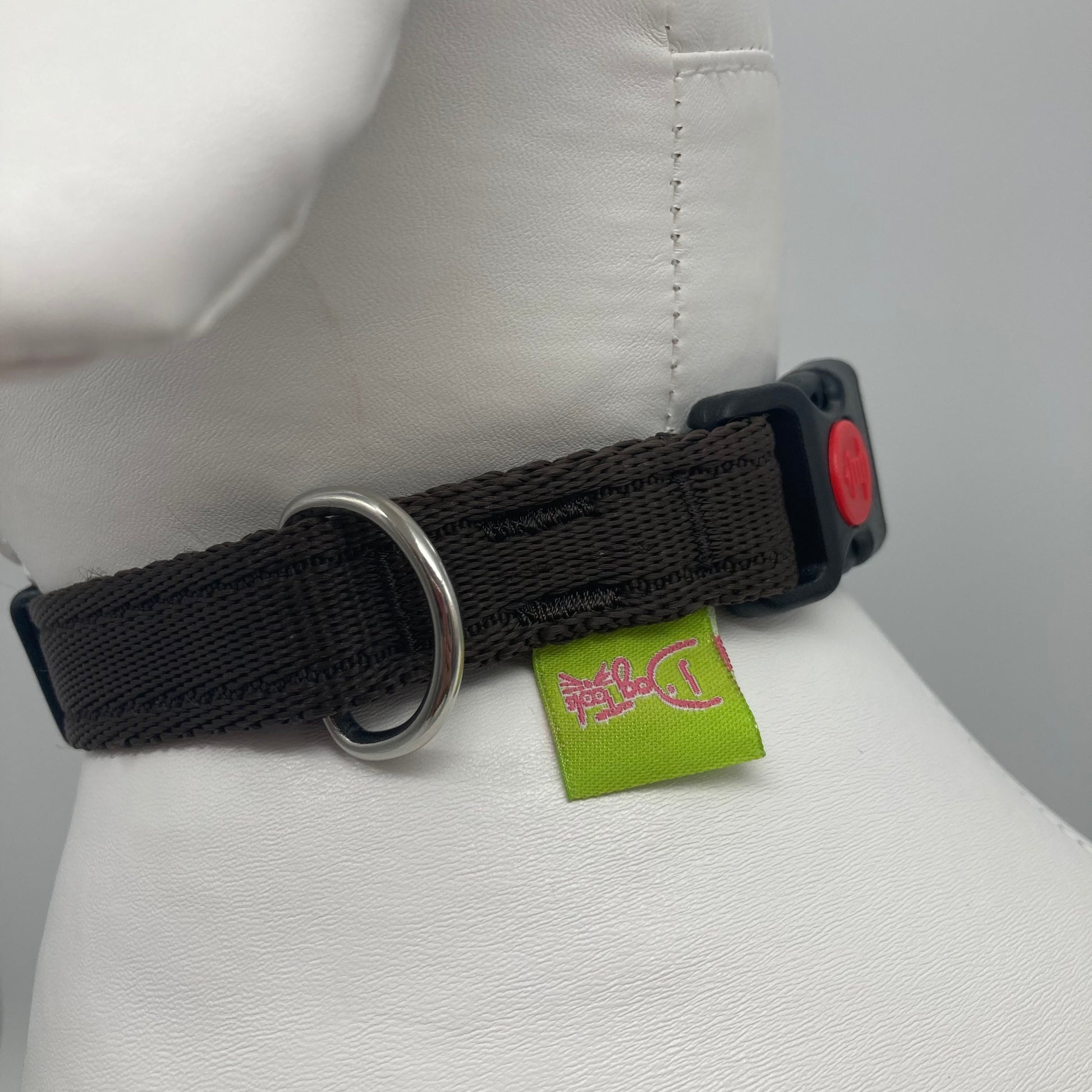 brown collar showing the black lock, stainless steel ring and the applegreen label with DogTools logo on it. Displayed on a stuffed toy (dog), around the neck