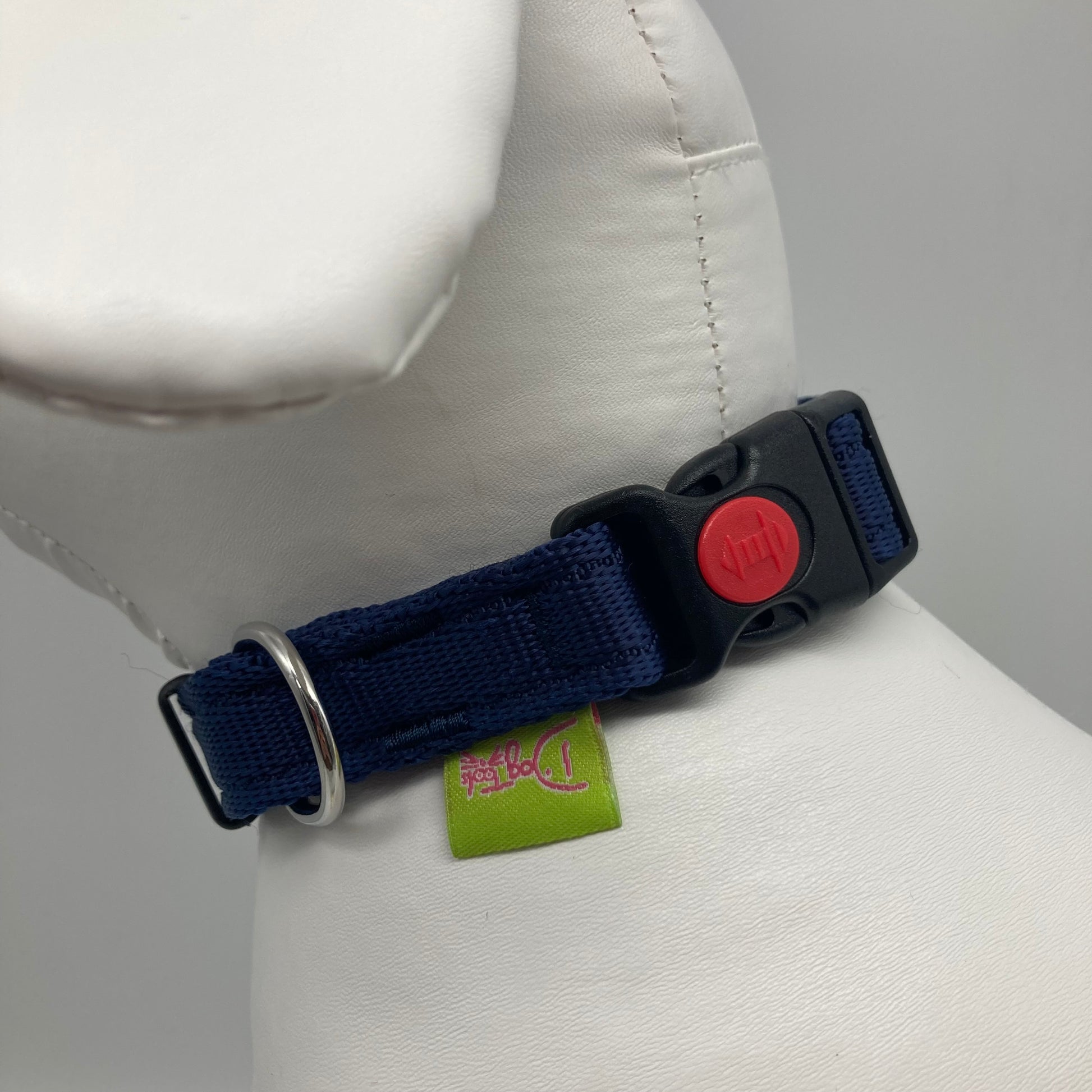 dark blue collar showing the black lock, stainless steel ring and the applegreen label with DogTools logo on it. Displayed on a stuffed toy (dog), around the neck