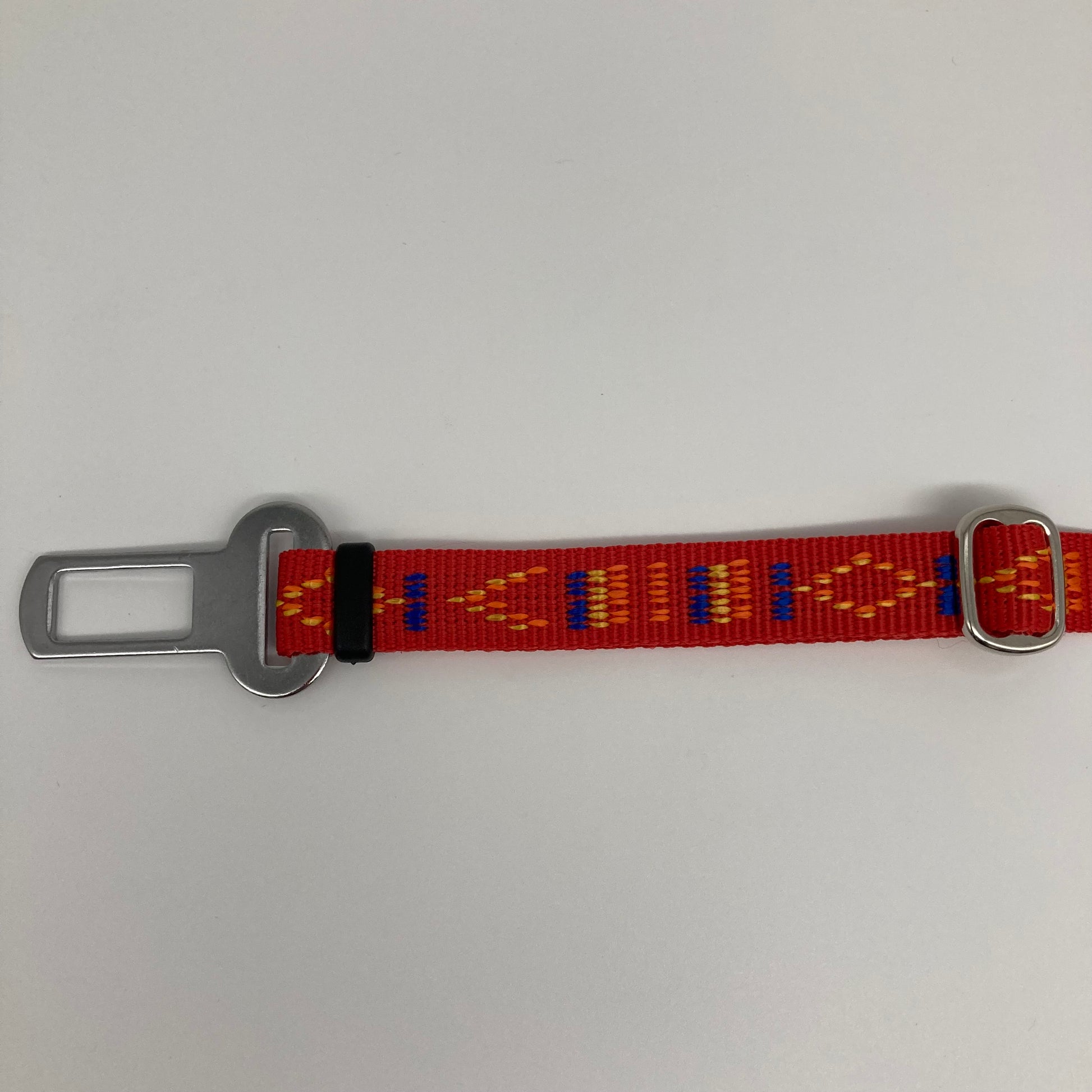 red Stitch (red fabric with print in 3 colors, yellow, orange and blue) car safety belt, showing the stainless steel buckle and the stainless steel clasp to adjust the length of the belt