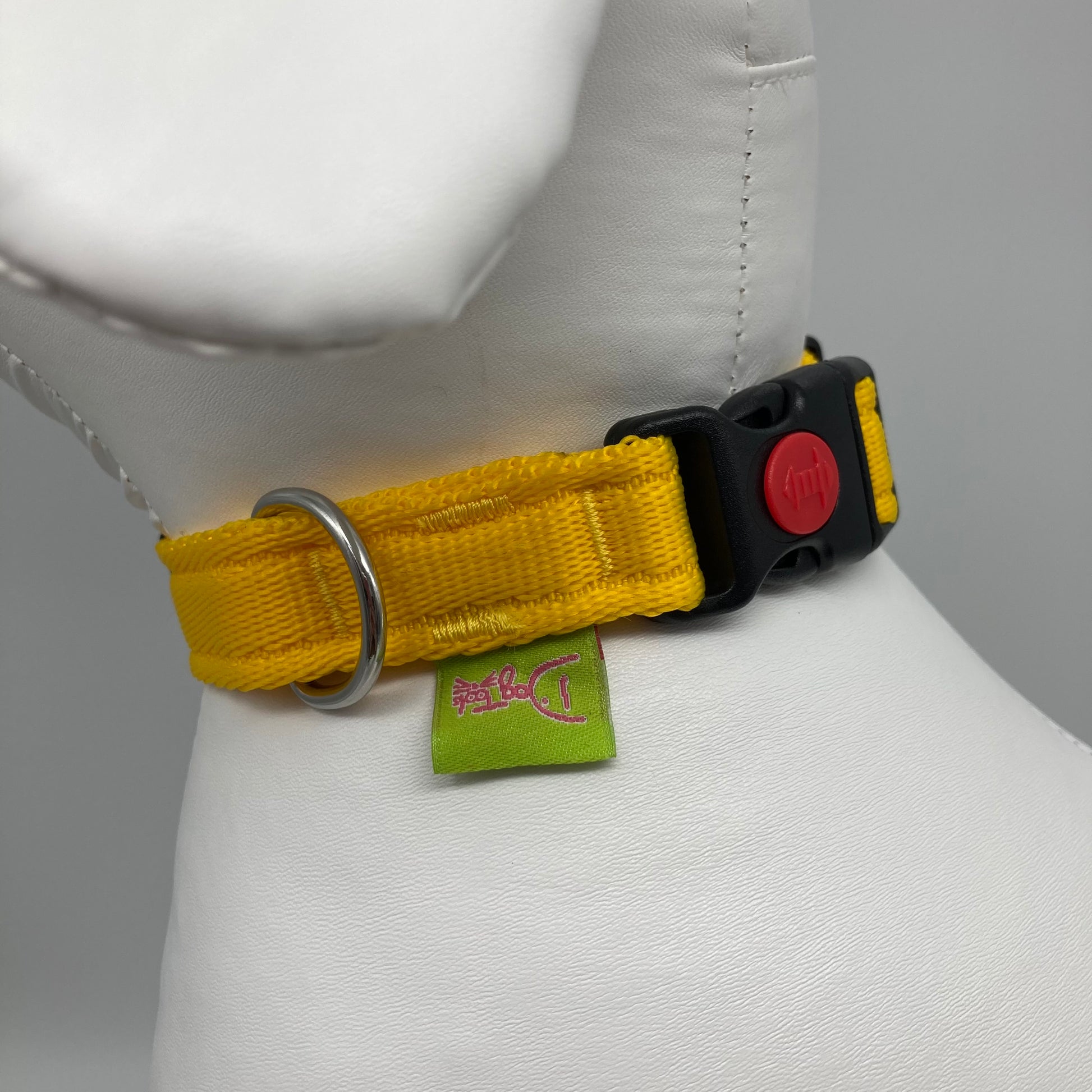 yellow collar showing the black lock, stainless steel ring and the applegreen label with DogTools logo on it. Displayed on a stuffed toy (dog), around the neck