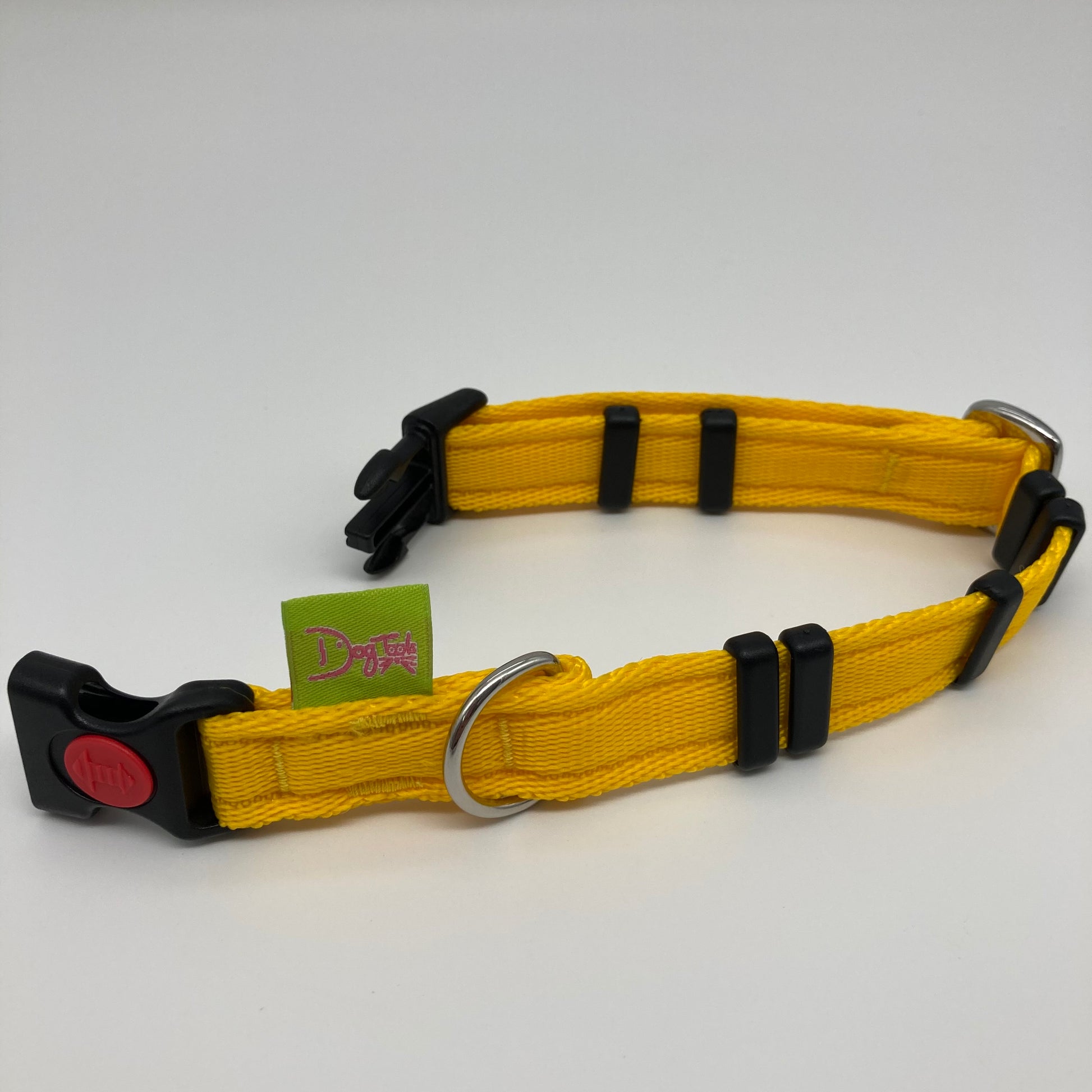 yellow collar displayed on a white surface, unlocked, showing the black lock, stainless steel ring, the black loops and the applegreen DogTools label