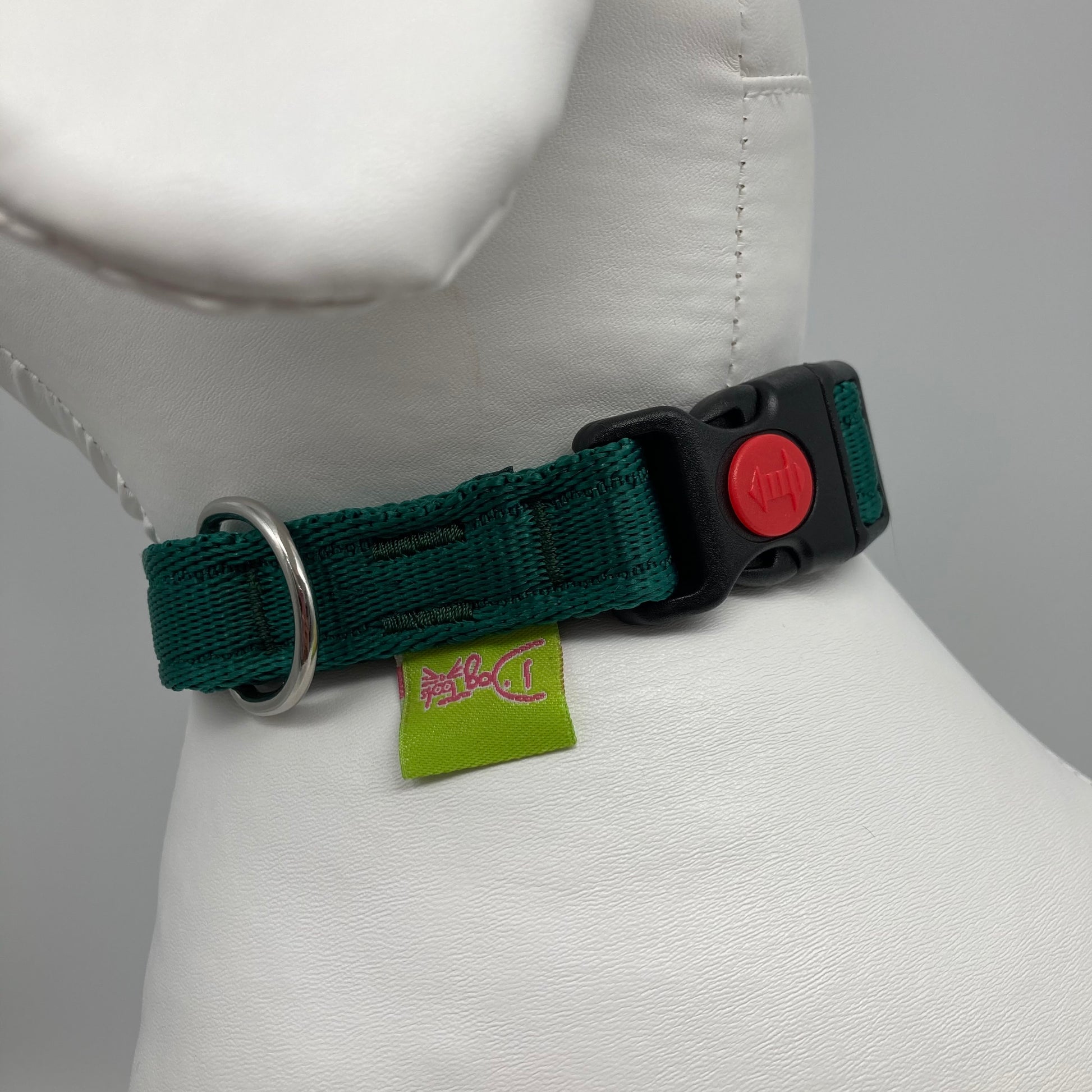green collar showing the black lock, stainless steel ring and the applegreen label with DogTools logo on it. Displayed on a stuffed toy (dog), around the neck