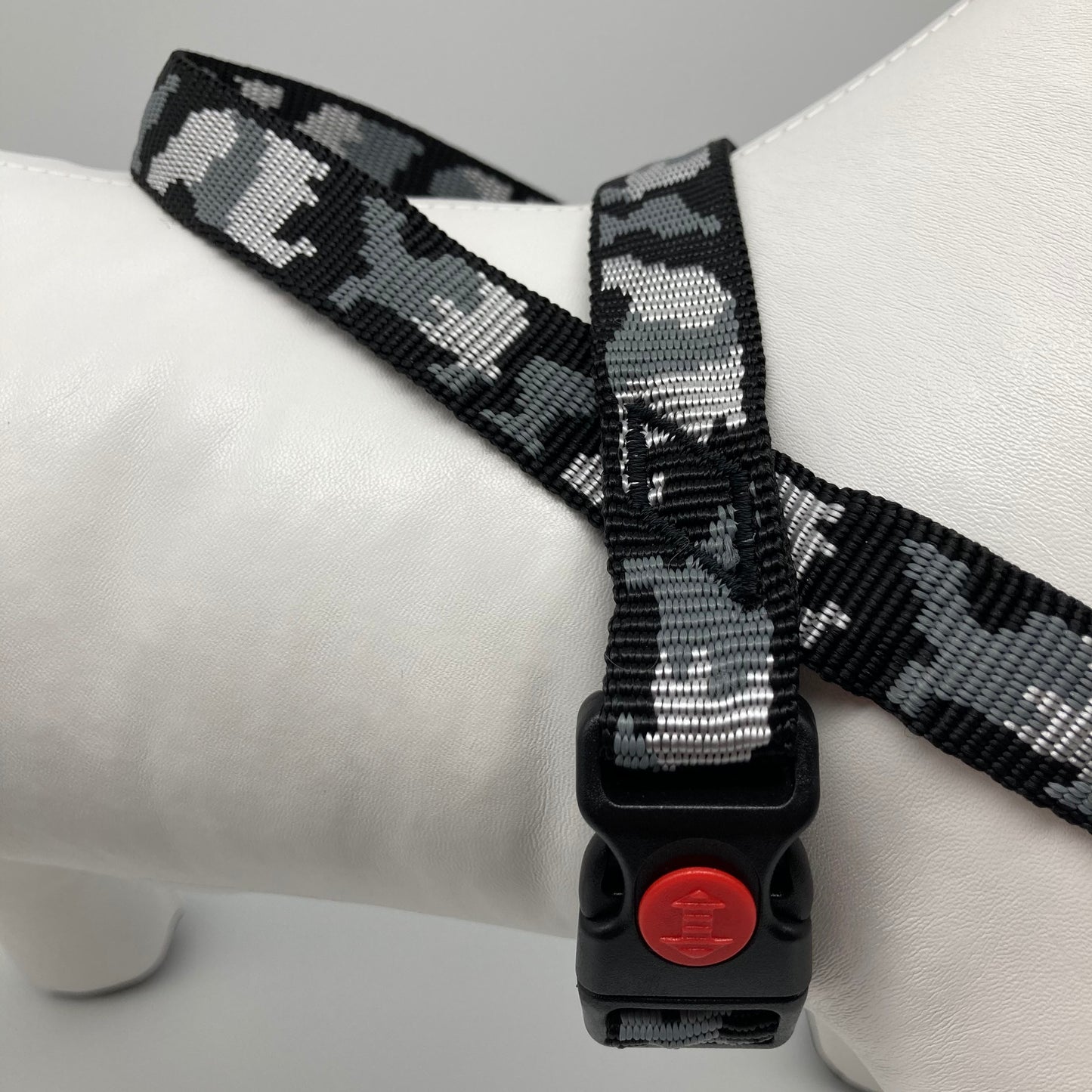 army grey (army print in 3 colors, dark grey, light grey and black) harness, displayed on a stuffed toy (dog), around the torso, showing the black lock and the loop on the back