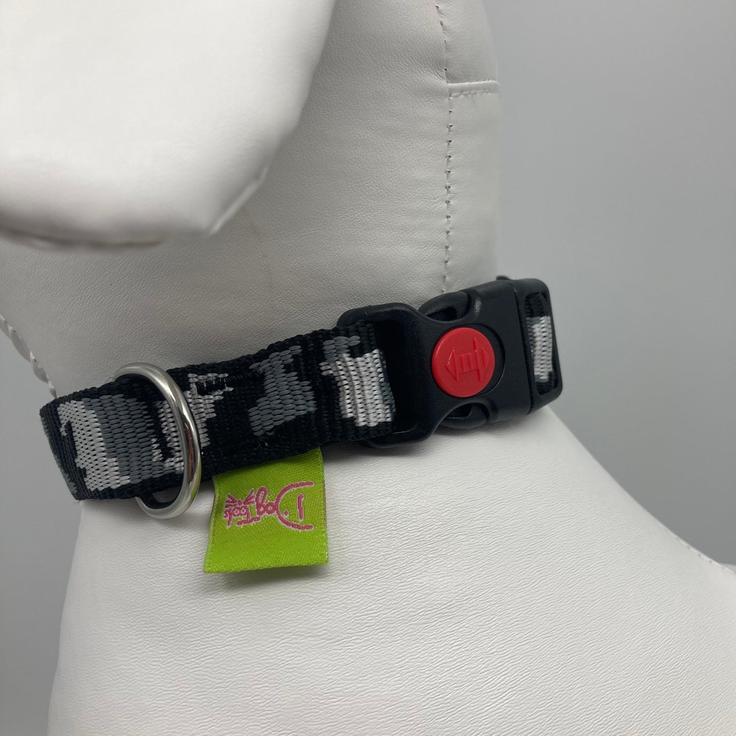 army grey (army print in 3 colors, dark grey, light grey and black) collar showing the black lock, stainless steel ring and the applegreen label with DogTools logo on it. Displayed on a stuffed toy (dog), around the neck