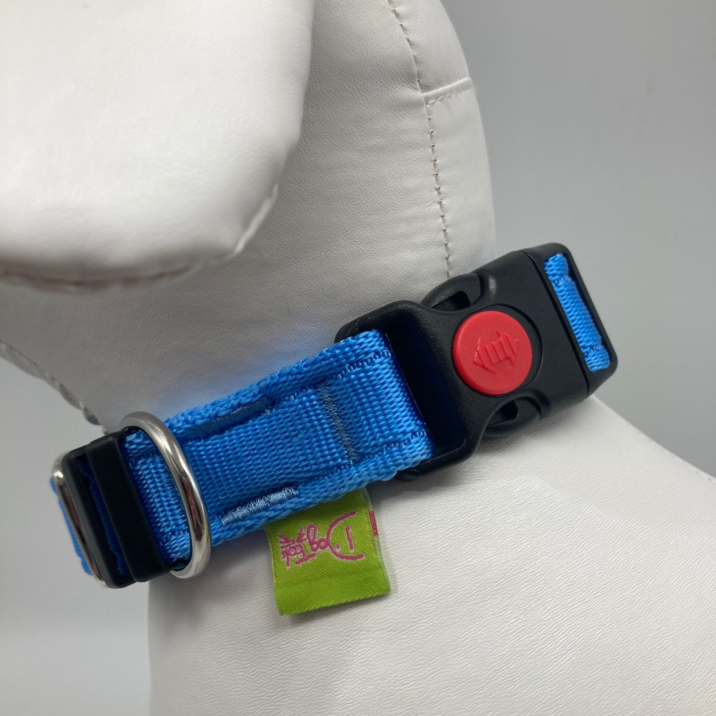 light blue collar showing the black lock, stainless steel ring and the applegreen label with DogTools logo on it. Displayed on a stuffed toy (dog), around the neck
