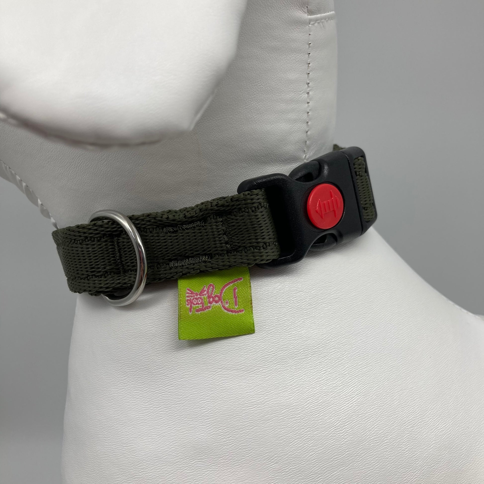 olive green collar showing the black lock, stainless steel ring and the applegreen label with DogTools logo on it. Displayed on a stuffed toy (dog), around the neck