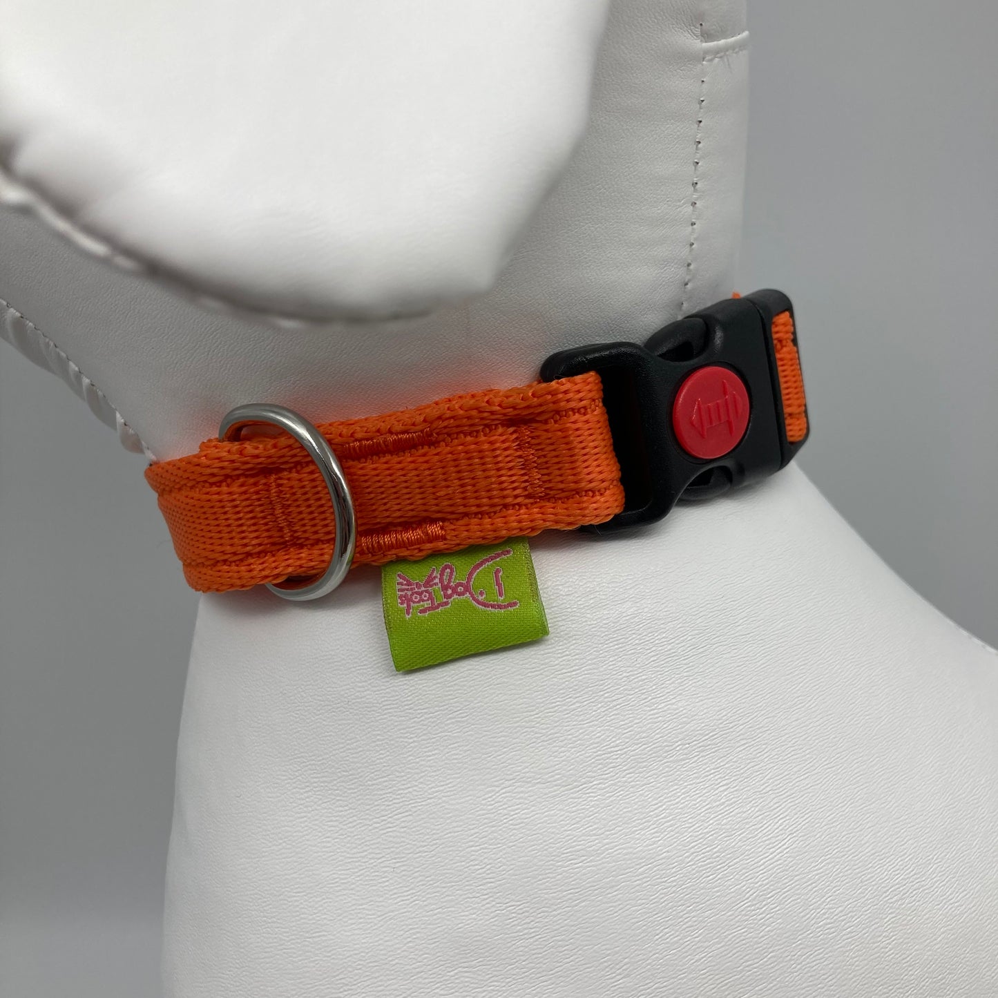 orange collar showing the black lock, stainless steel ring and the applegreen label with DogTools logo on it. Displayed on a stuffed toy (dog), around the neck