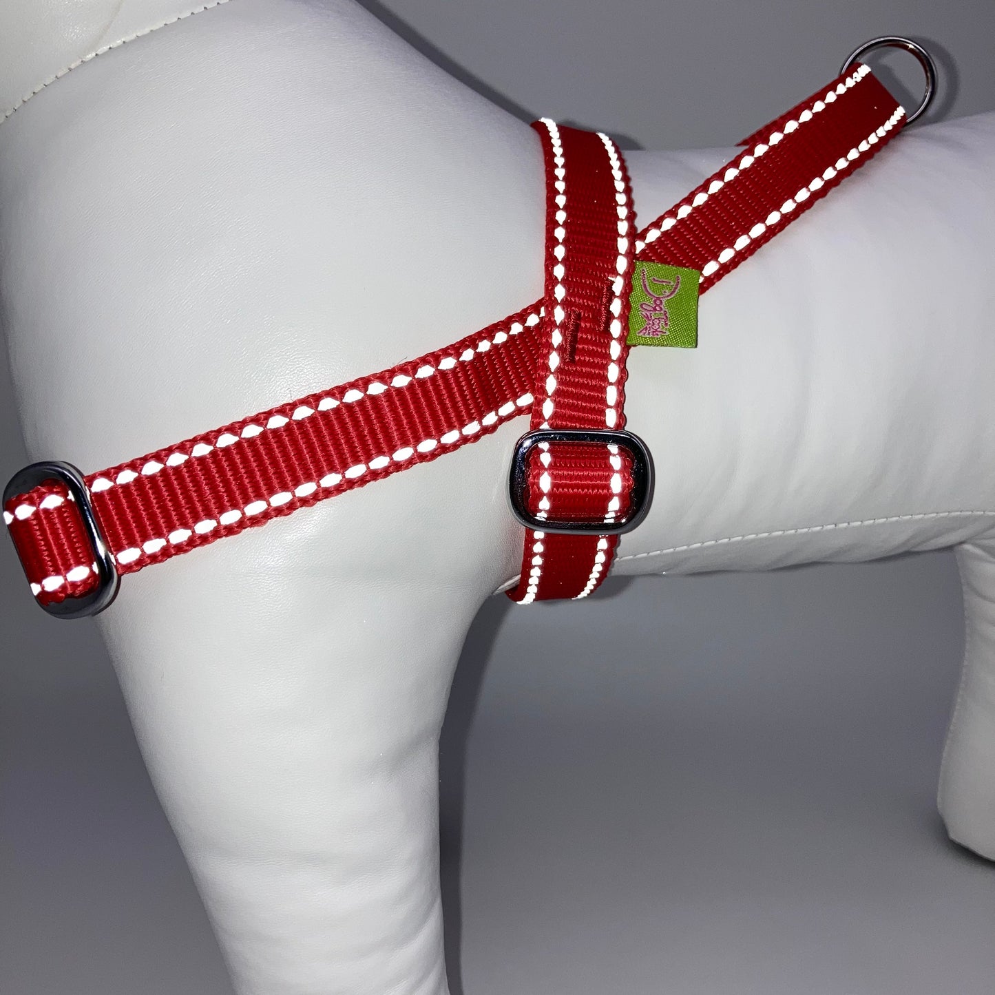 red harness with light reflecting stitches, from the side, showing the loop, the stainless steel parts and the applegreen label