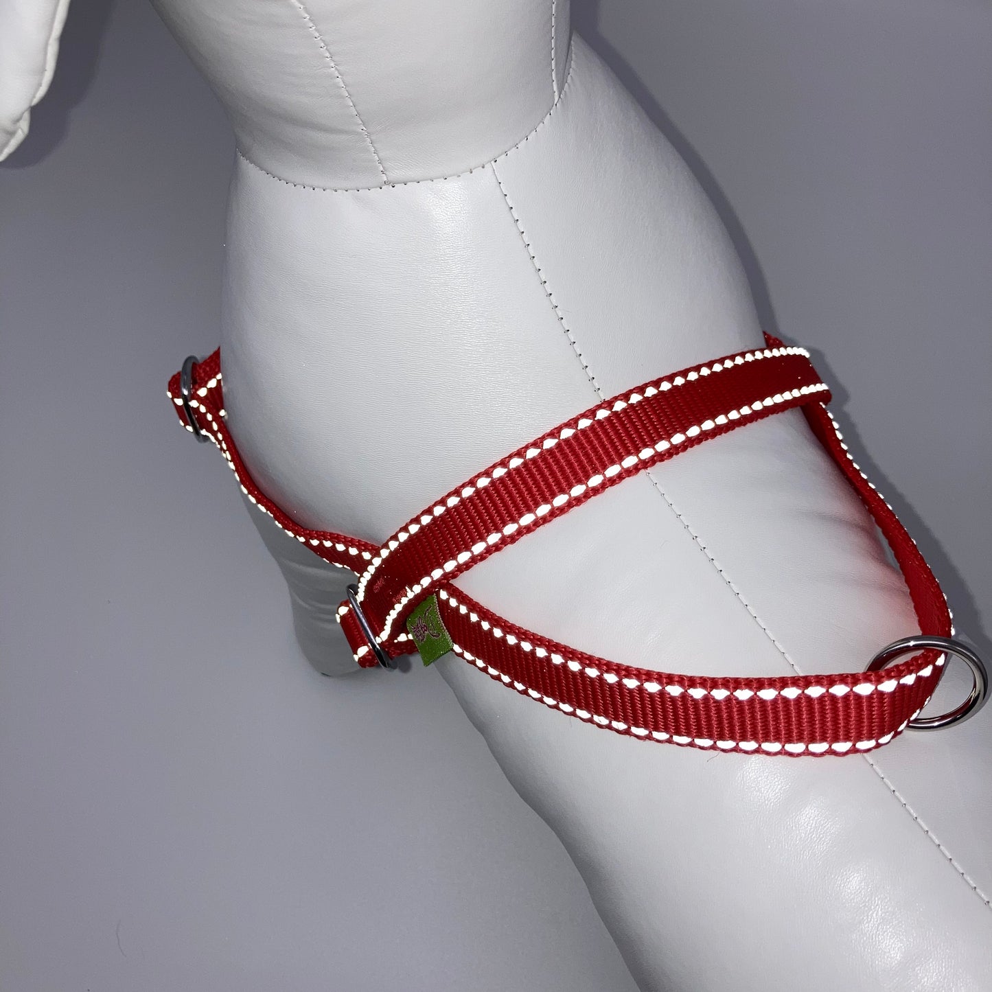 red harness with light reflecting stitches, showing the back from above, showing the loop, the stainless steel ring and the applegreen label