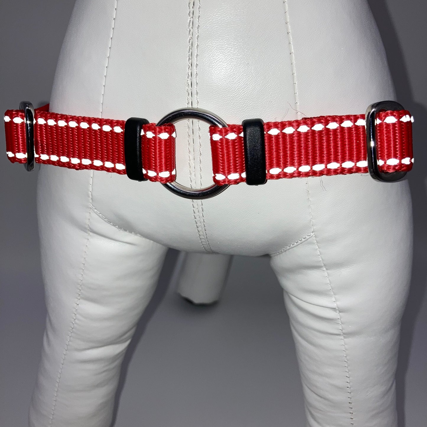 red harness with light reflecting stitches, showing the chest from the front, the stainless steel ring where the leash is attached to