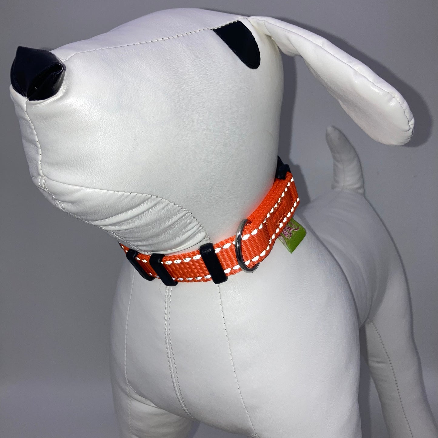 orange collar with light reflecting stitches displayed on a stuffed toy (dog), from the front of the dog, showing its head and torso