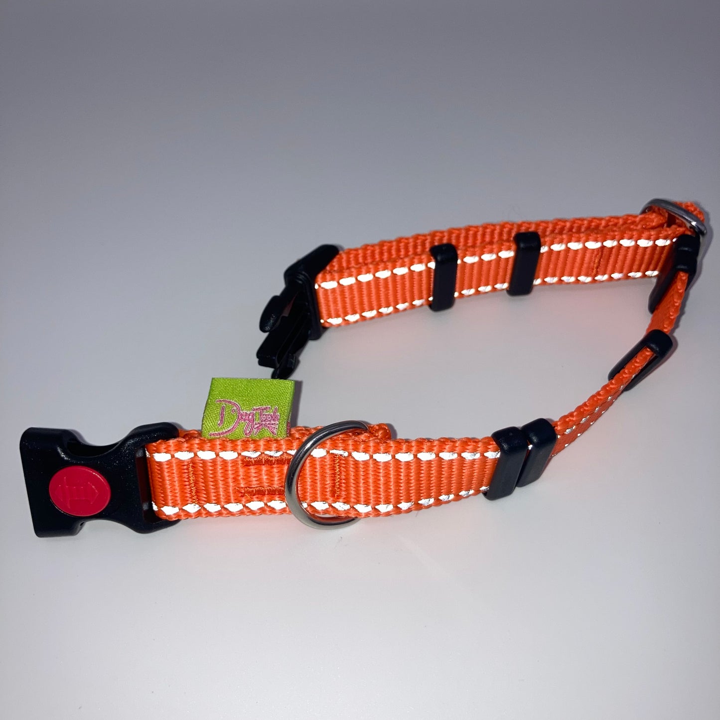 orange collar with light reflecting stitches displayed on a white surface, unlocked, showing the black lock, stainless steel ring, the black loops and the applegreen DogTools label