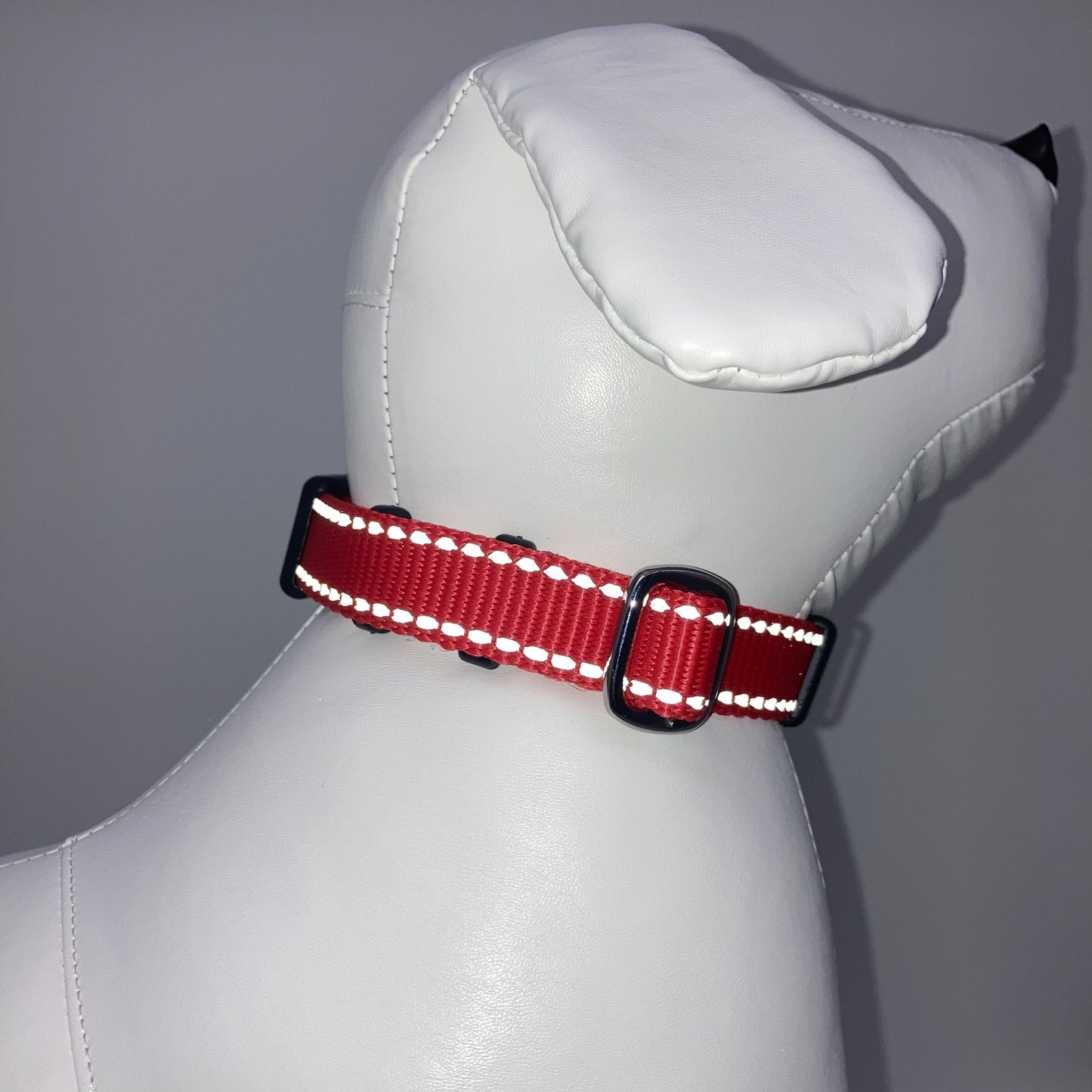 red collar with light reflecting stitches displayed on a stuffed toy (dog), showing the back of the head and the collar from behind