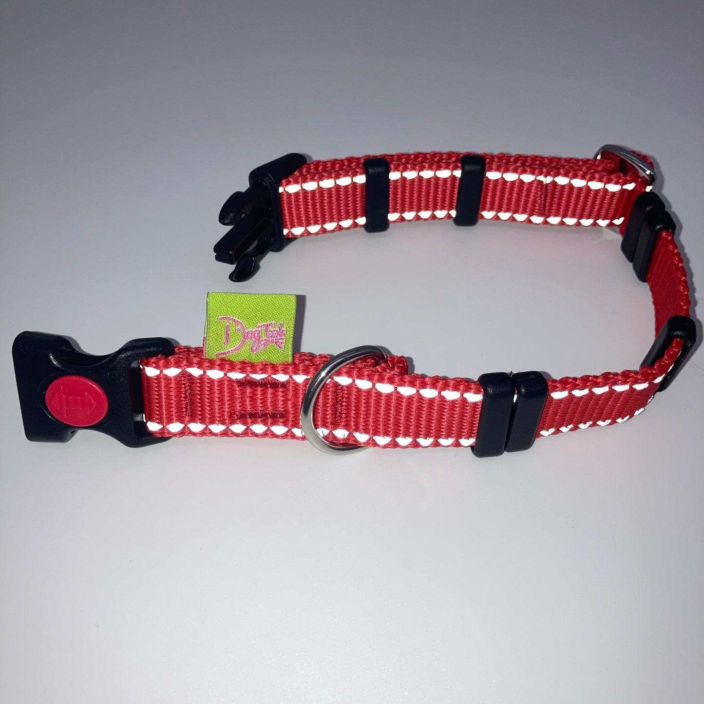 red collar with light reflecting stitches displayed on a white surface, unlocked, showing the black lock, stainless steel ring, the black loops and the applegreen DogTools label