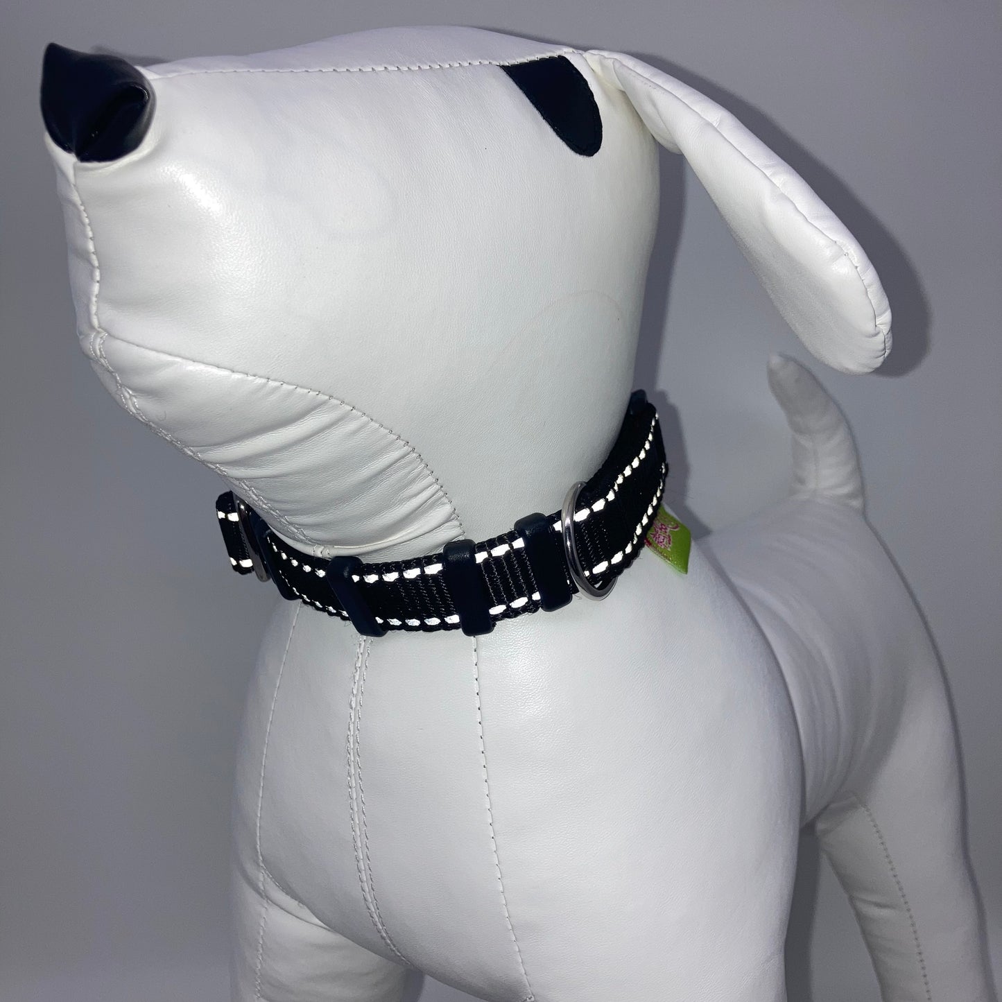 black collar with light reflecting stitches displayed on a stuffed toy (dog), from the front of the dog, showing its head and torso