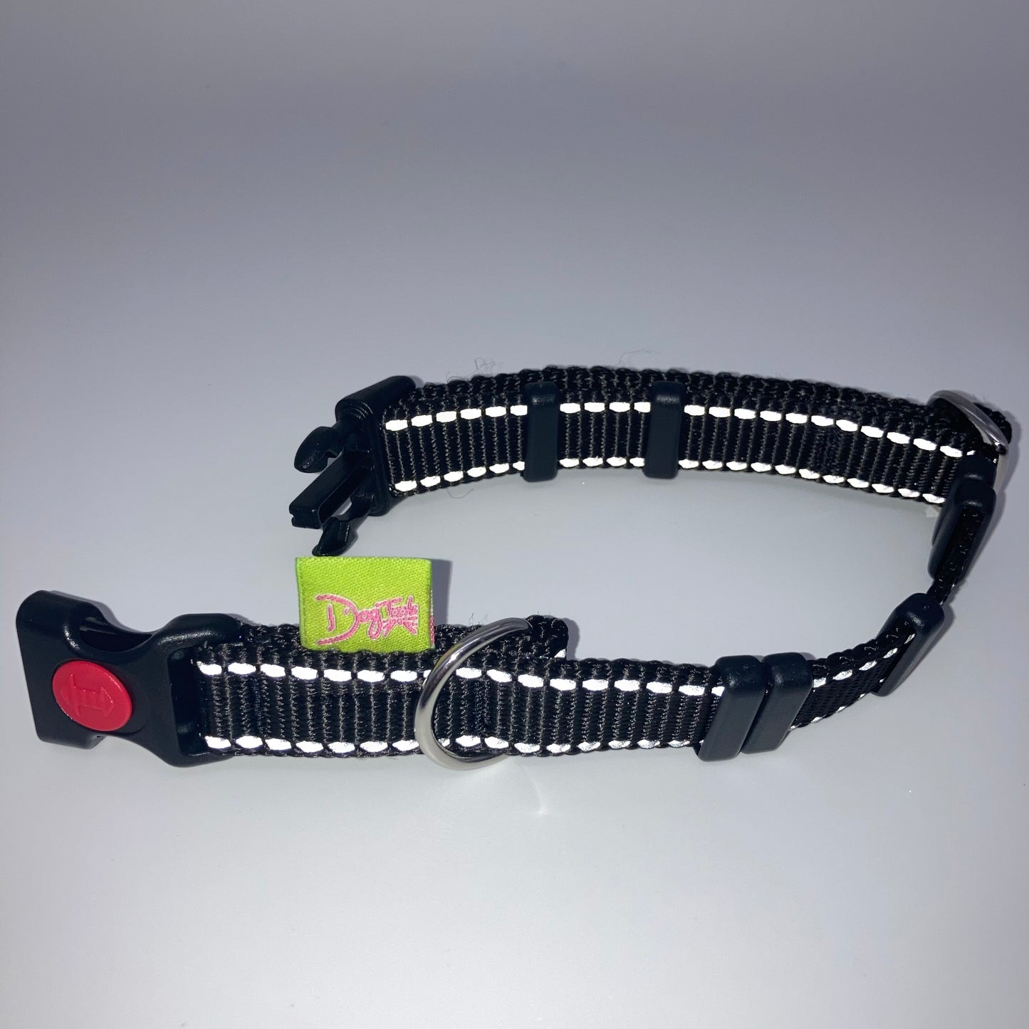 black collar with light reflecting stitches displayed on a white surface, unlocked, showing the black lock, stainless steel ring, the black loops and the applegreen DogTools label