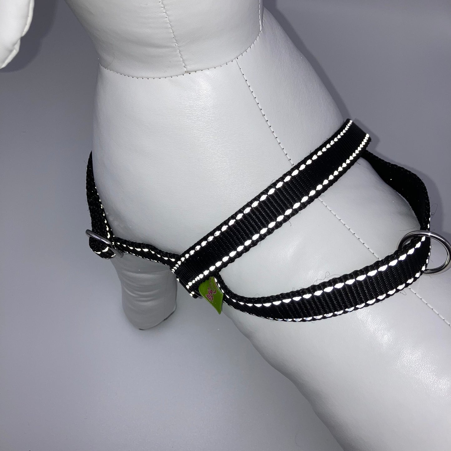 black harness with light reflecting stitches, showing the back from above, showing the loop, the stainless steel ring and the applegreen label