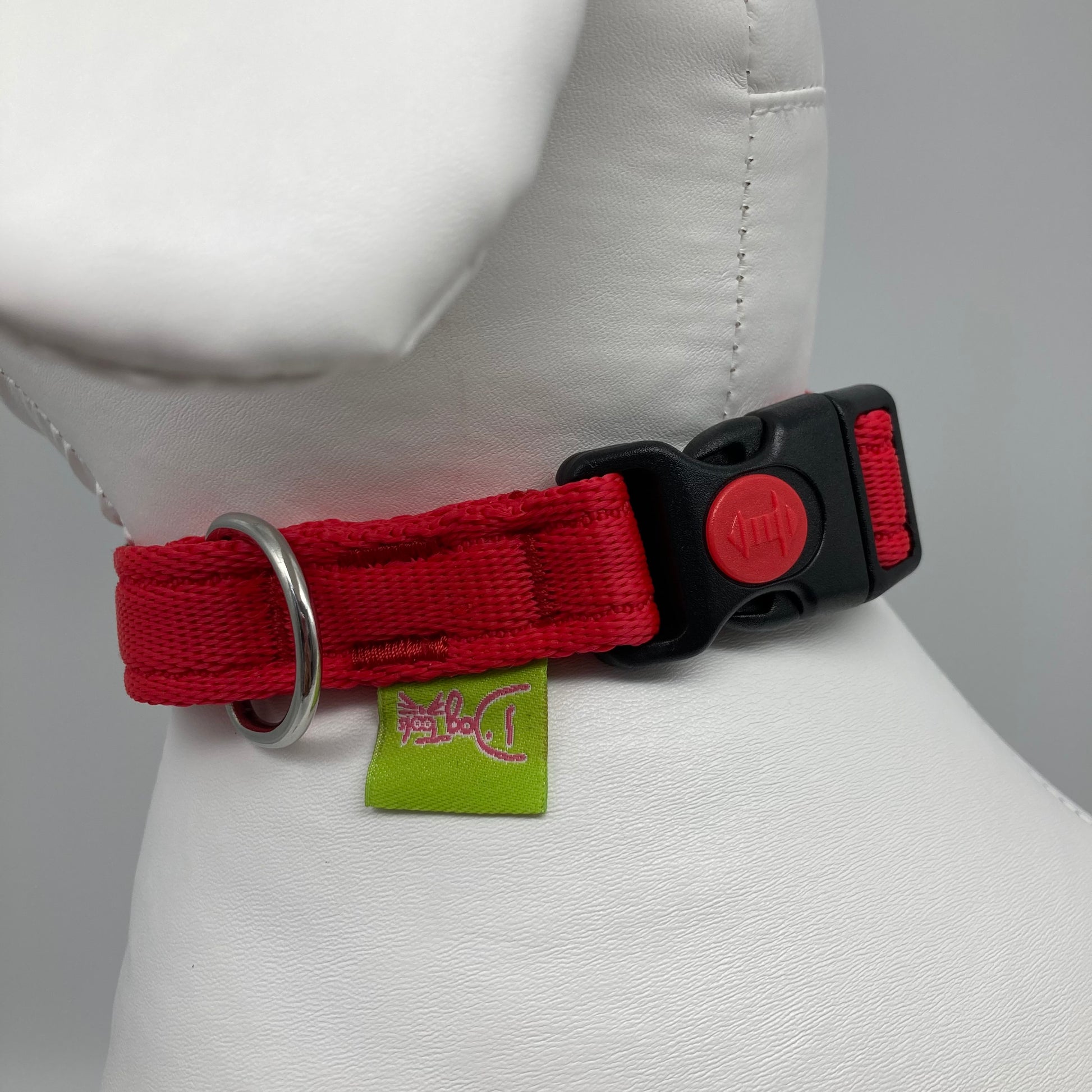 red collar showing the black lock, stainless steel ring and the applegreen label with DogTools logo on it. Displayed on a stuffed toy (dog), around the neck