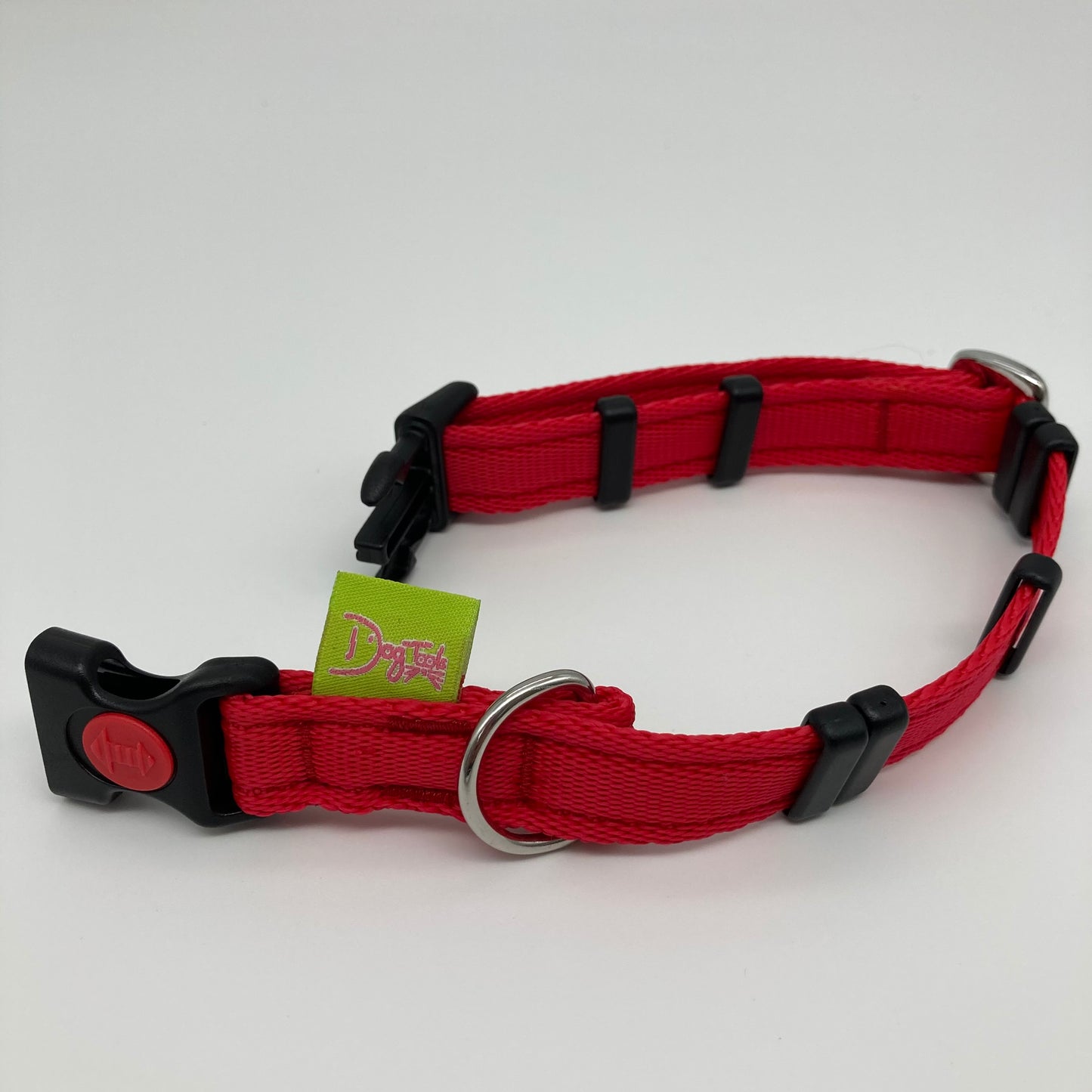 red collar displayed on a white surface, unlocked, showing the black lock, stainless steel ring, the black loops and the applegreen DogTools label