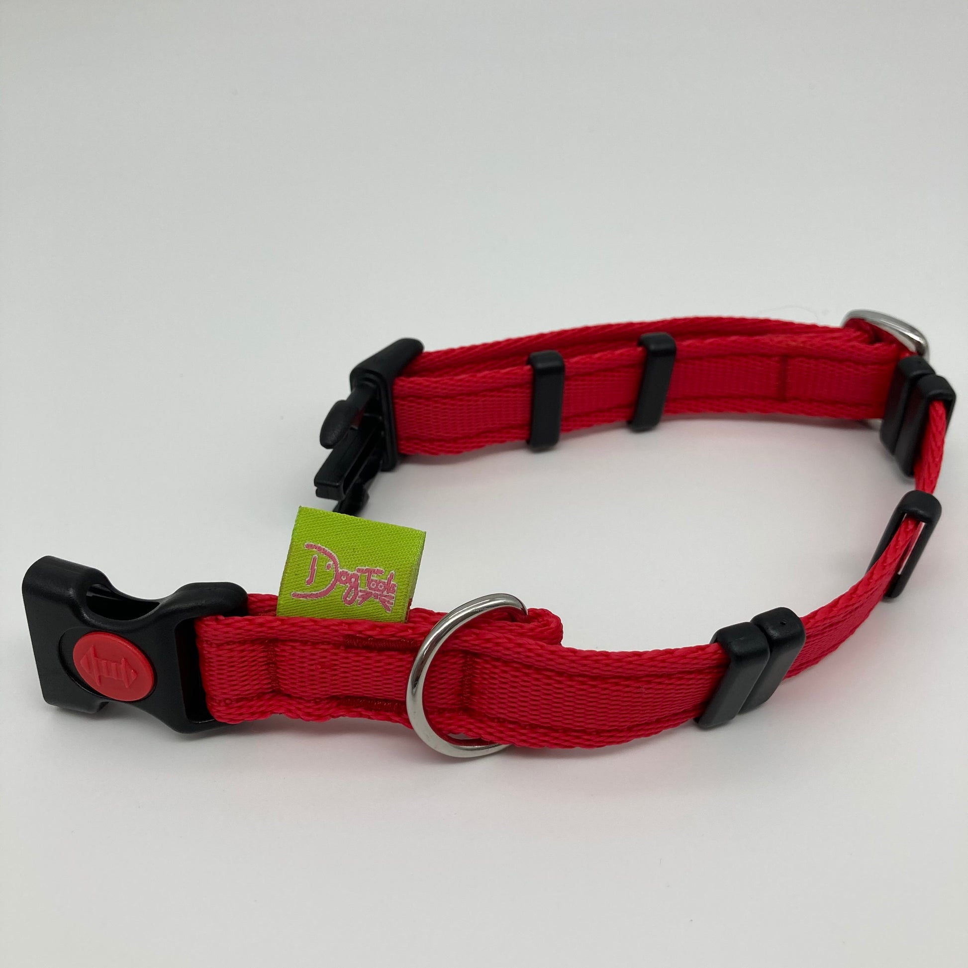 red collar displayed on a white surface, unlocked, showing the black lock, stainless steel ring, the black loops and the applegreen DogTools label