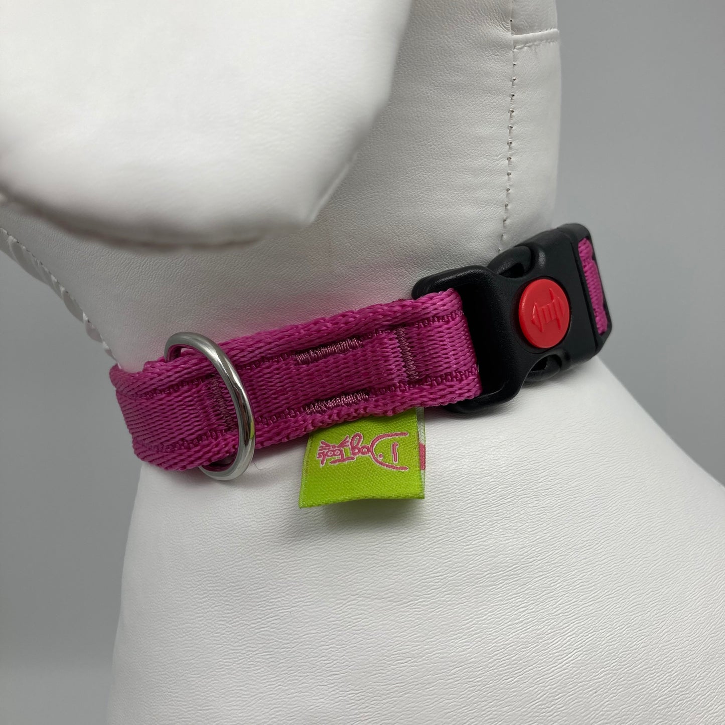 pink collar showing the black lock, stainless steel ring and the applegreen label with DogTools logo on it. Displayed on a stuffed toy (dog), around the neck