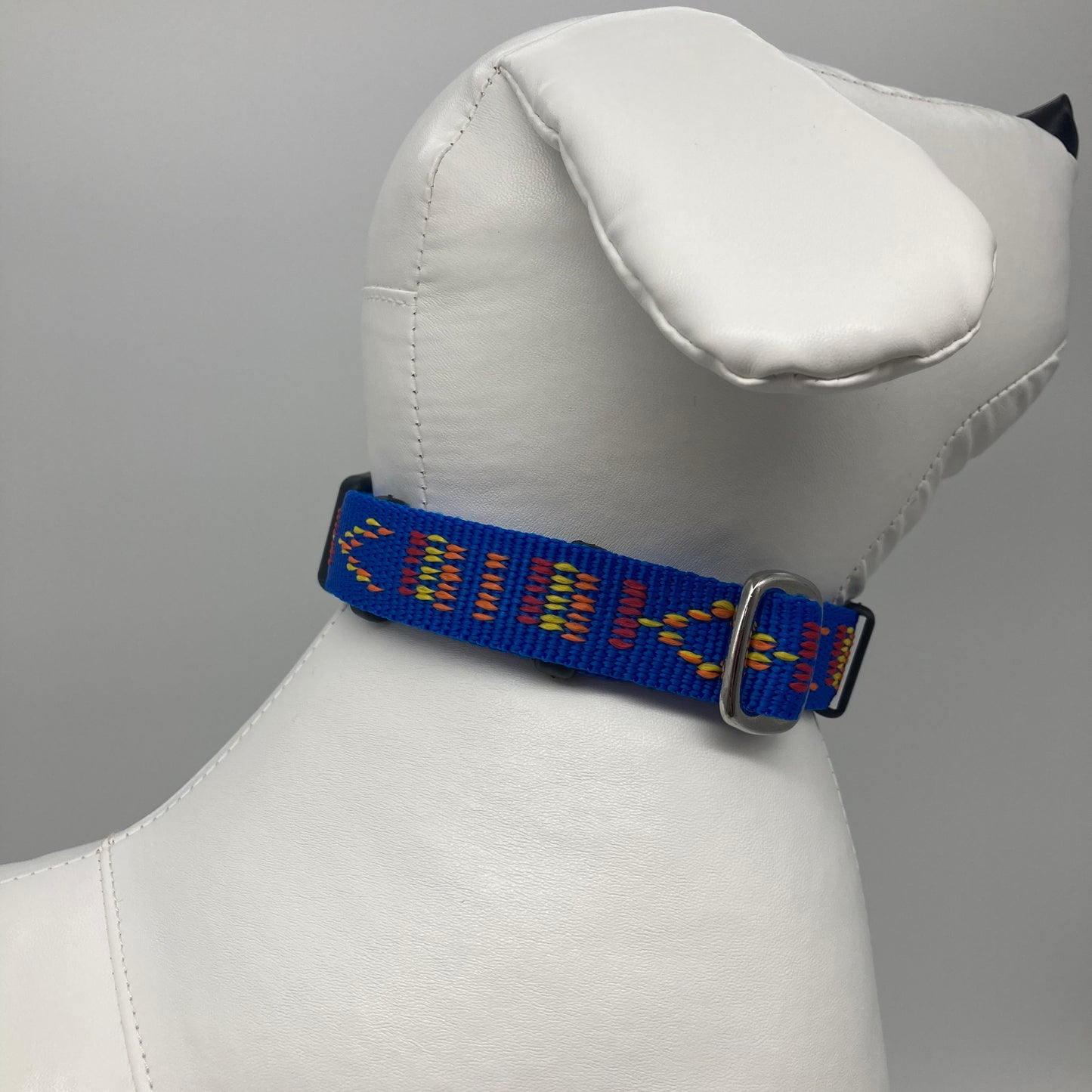 blue Stitch (blue fabric with print in 3 colors, red, yellow and orange) collar displayed on a stuffed toy (dog), showing the back of the head and the collar from behind