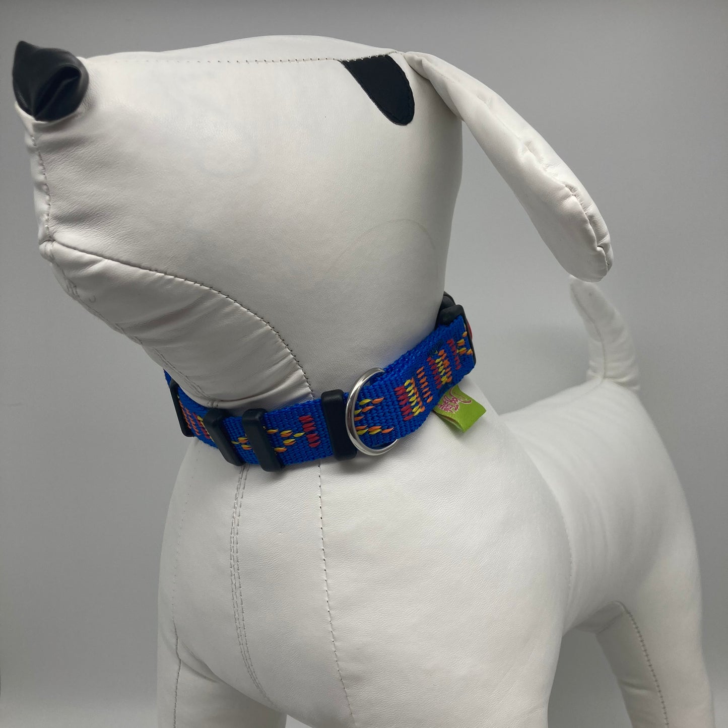 blue Stitch (blue fabric with print in 3 colors, red, yellow and orange) collar displayed on a stuffed toy (dog), from the front of the dog, showing its head and torso
