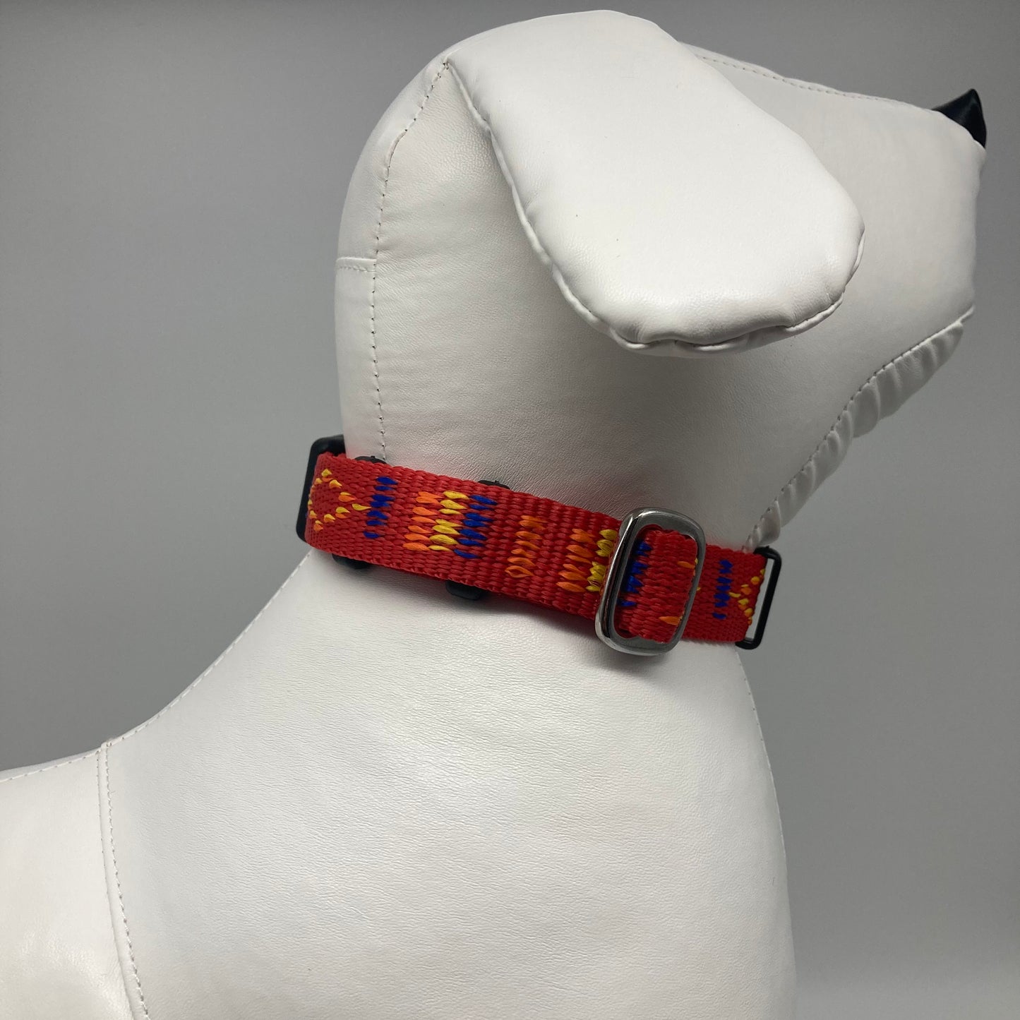 red Stitch (red fabric with print in 3 colors, yellow, orange and blue) collar displayed on a stuffed toy (dog), showing the back of the head and the collar from behind