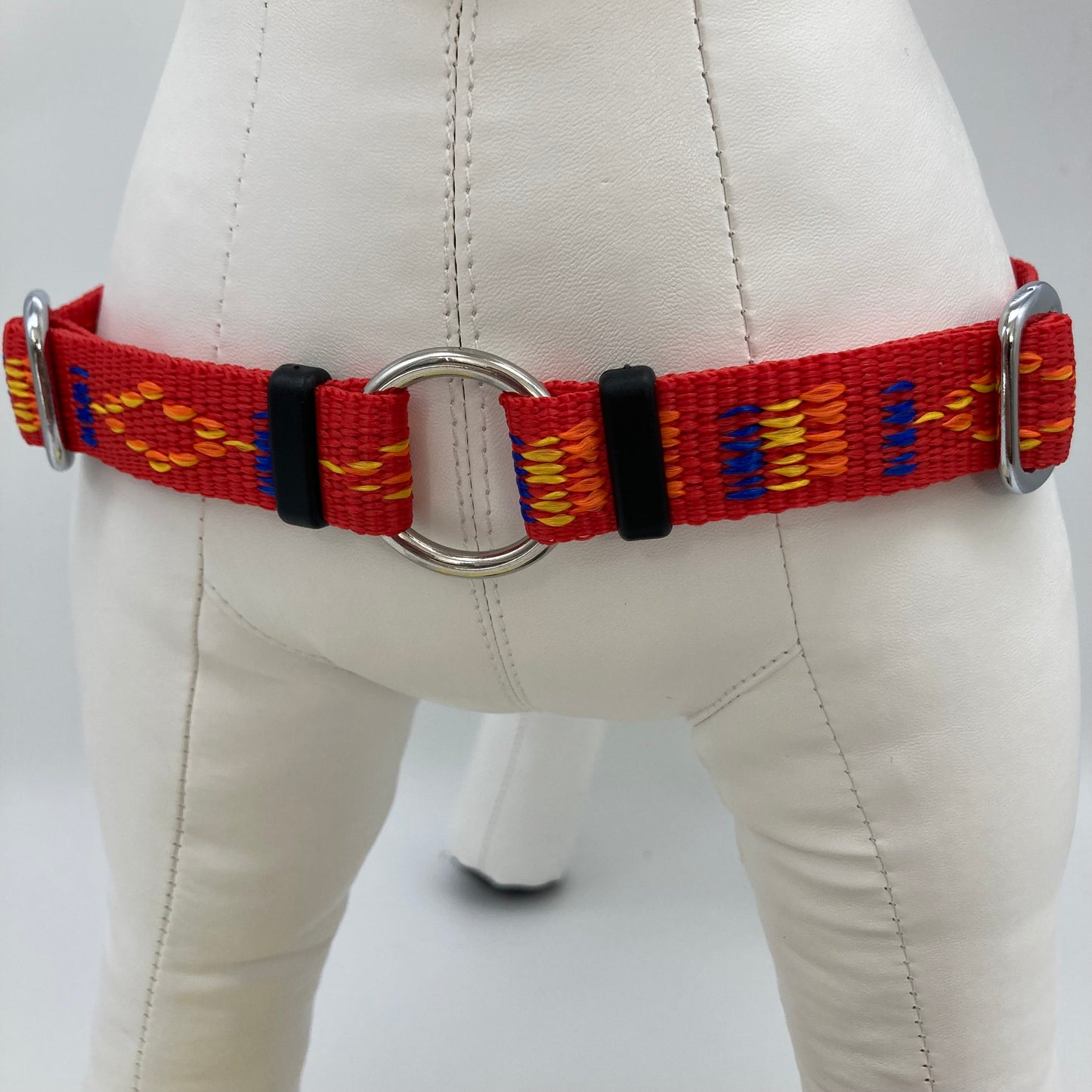red Stitch (red fabric with print in 3 colors, yellow, orange and blue) harness, showing the chest from the front, the stainless steel ring where the leash is attached to