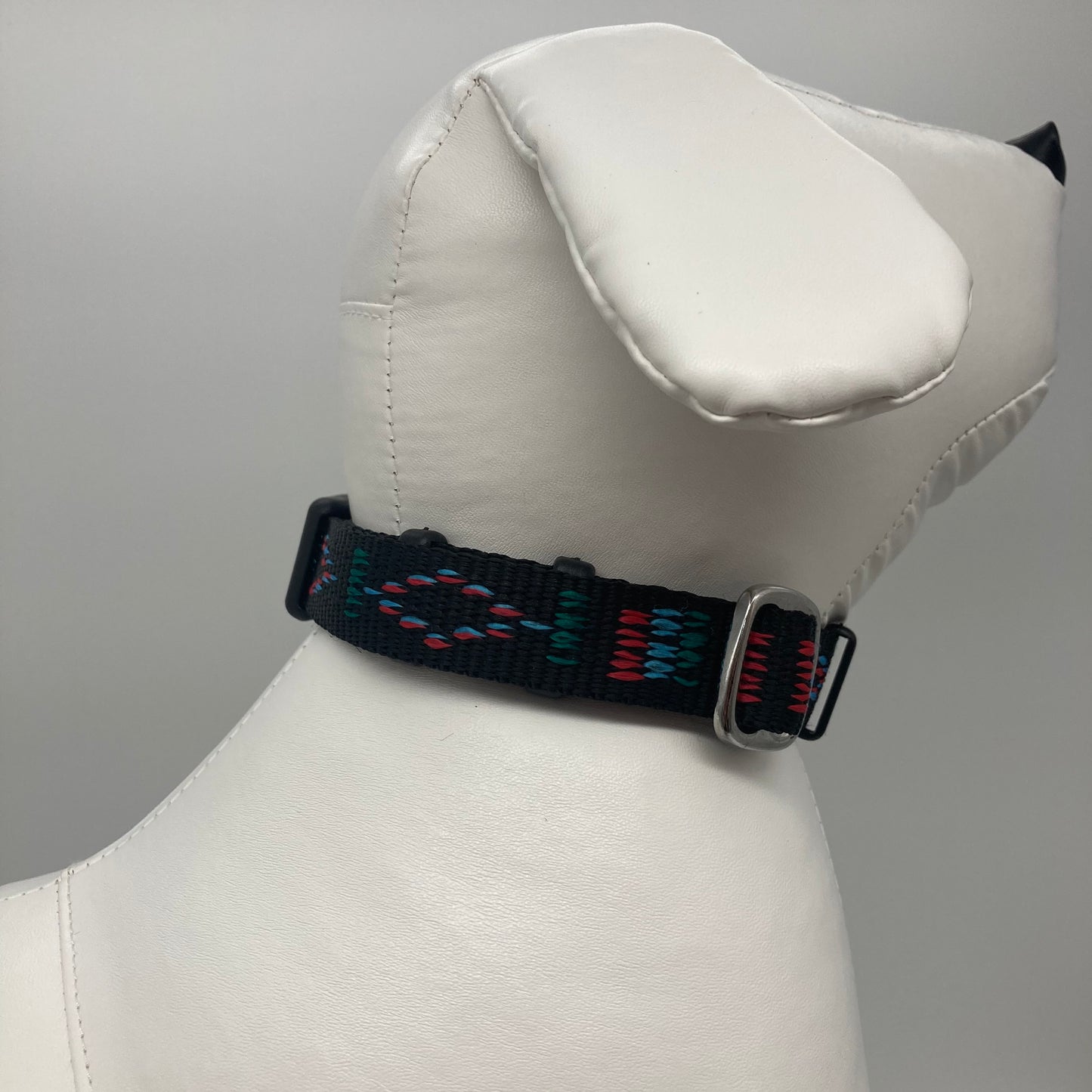 Stitch black (black fabric with print in 3 colors, red, light blue and green) collar displayed on a stuffed toy (dog), showing the back of the head and the collar from behind