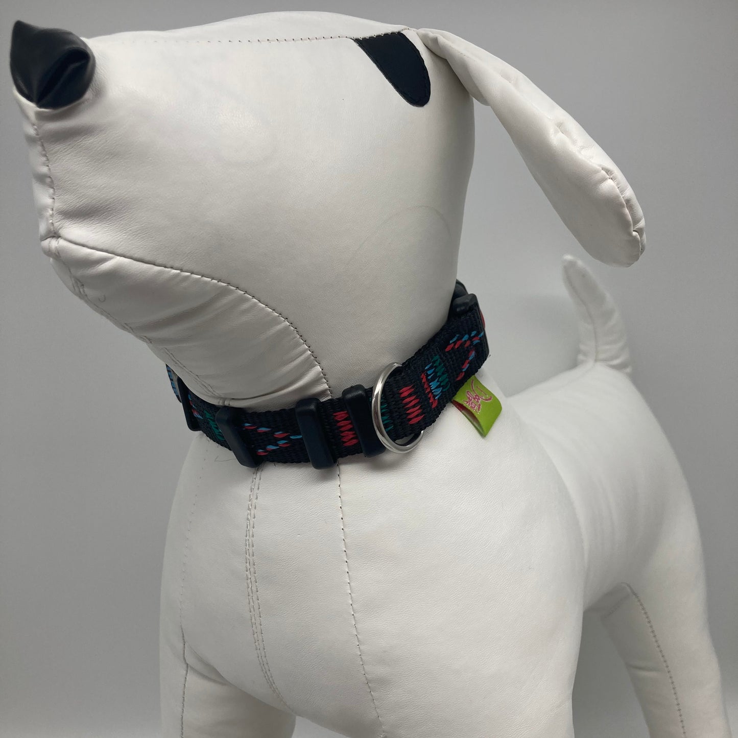 Stitch black (black fabric with print in 3 colors, red, light blue and green) collar displayed on a stuffed toy (dog), from the front of the dog, showing its head and torso