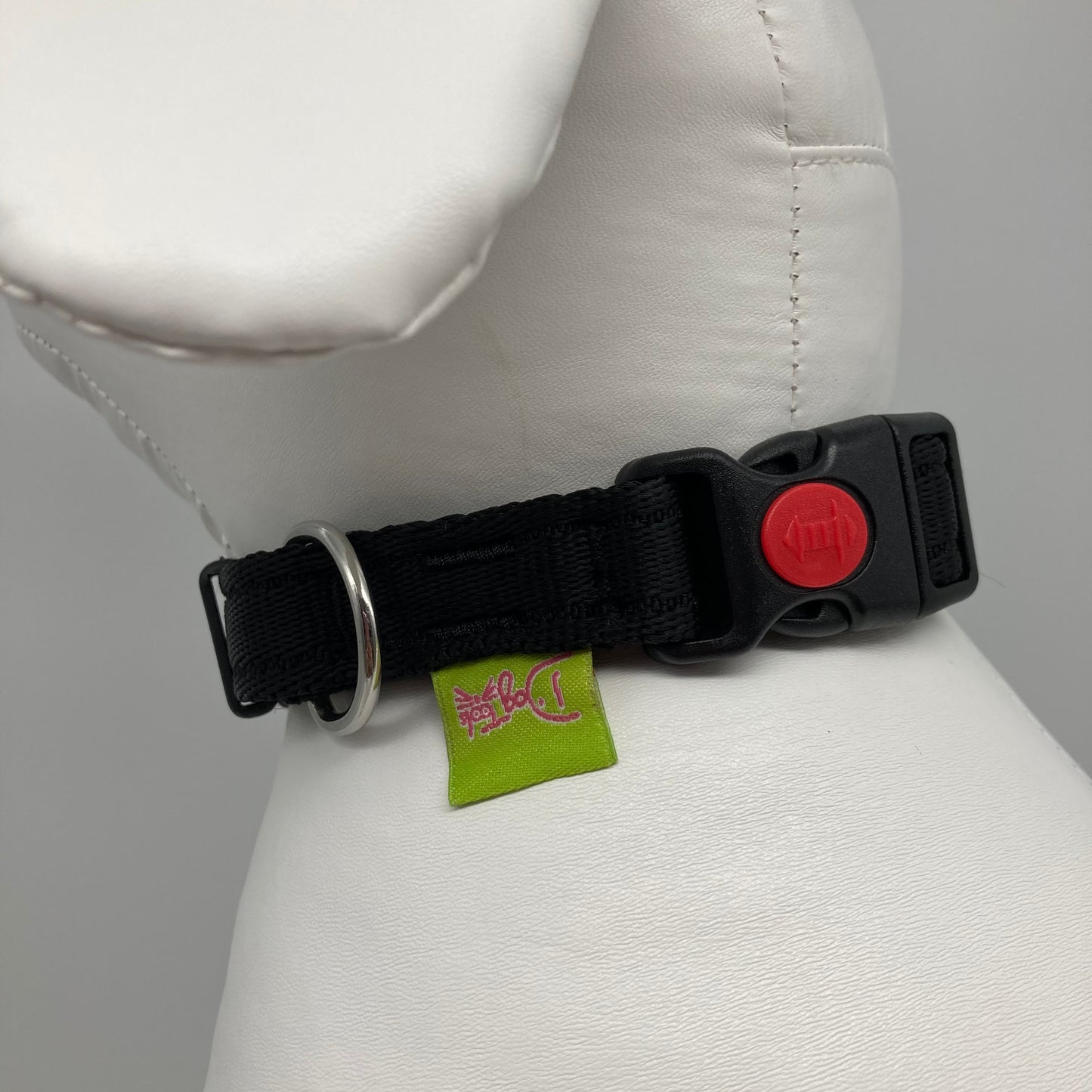 black collar showing the black lock, stainless steel ring and the applegreen label with DogTools logo on it. Displayed on a stuffed toy (dog), around the neck