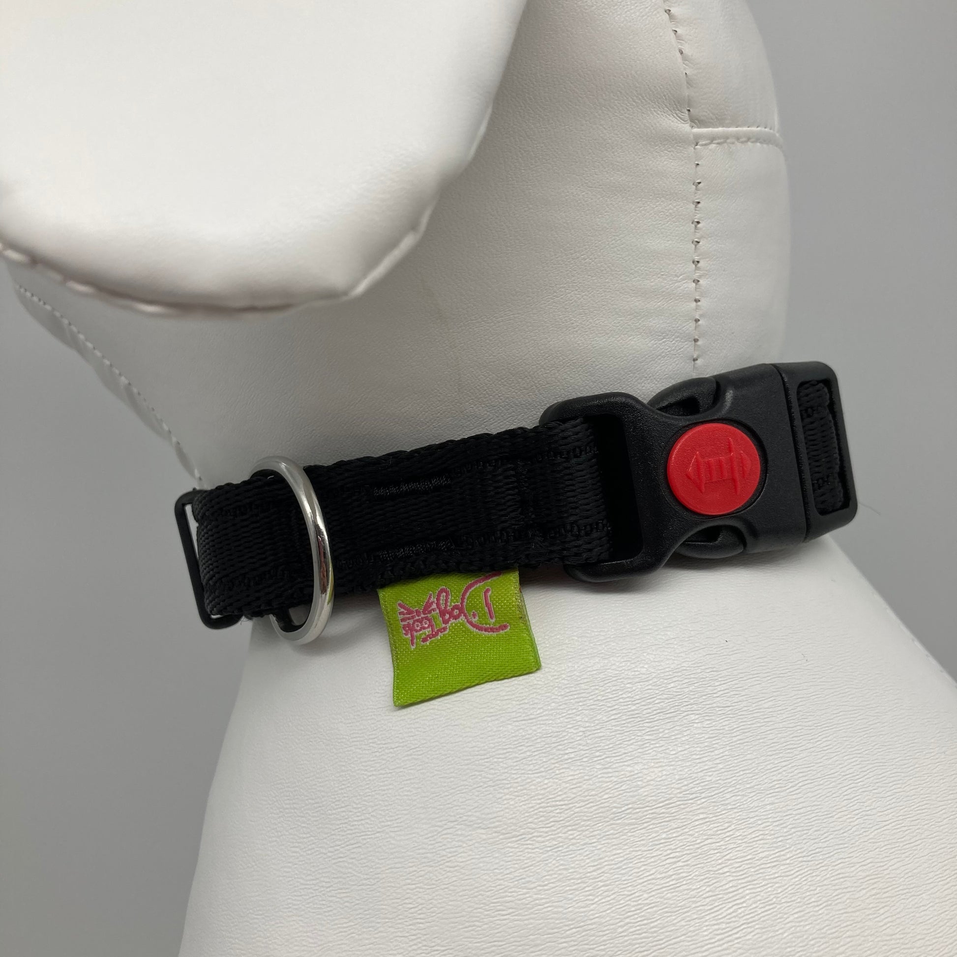 black collar showing the black lock, stainless steel ring and the applegreen label with DogTools logo on it. Displayed on a stuffed toy (dog), around the neck