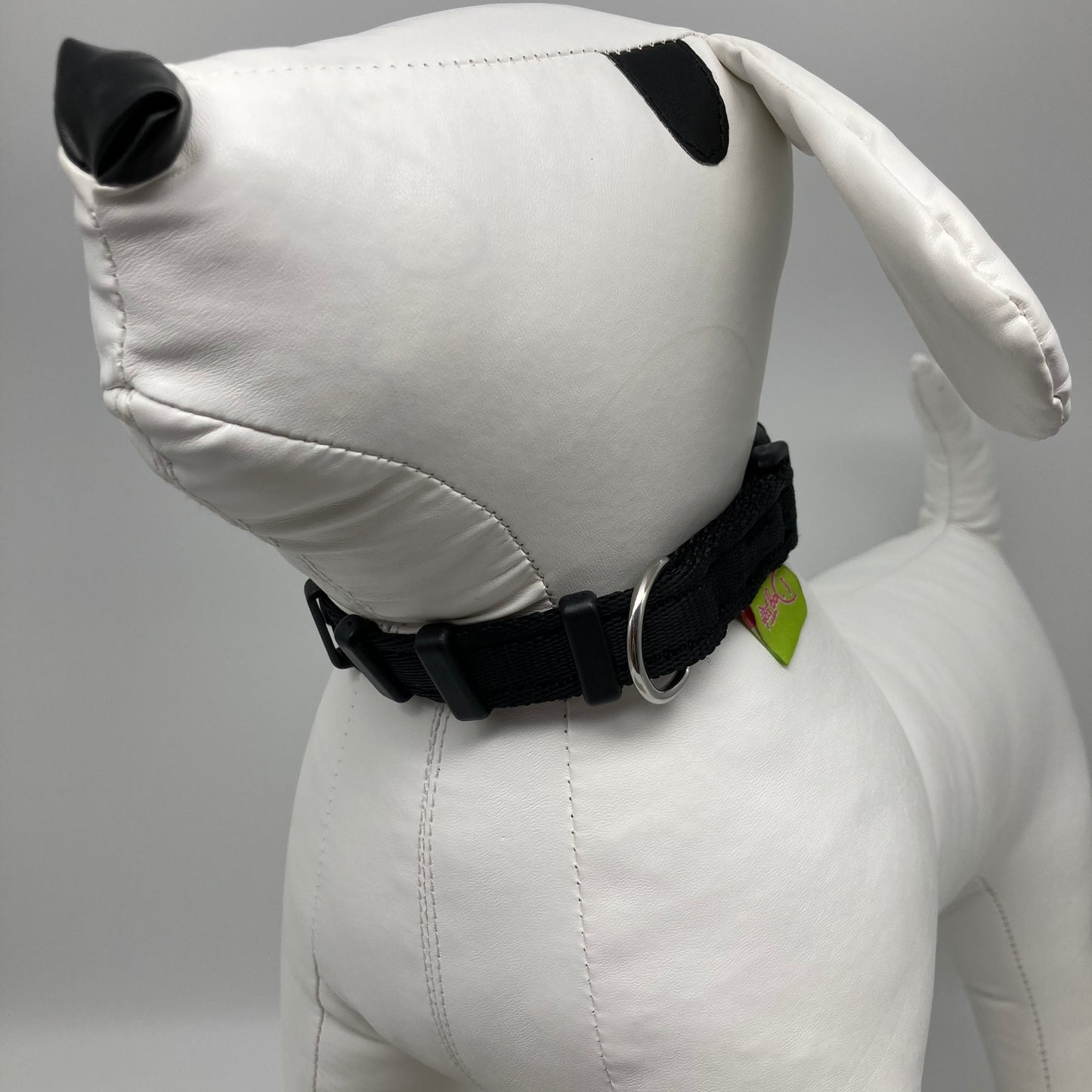 black collar displayed on a stuffed toy (dog), from the front of the dog, showing its head and torso