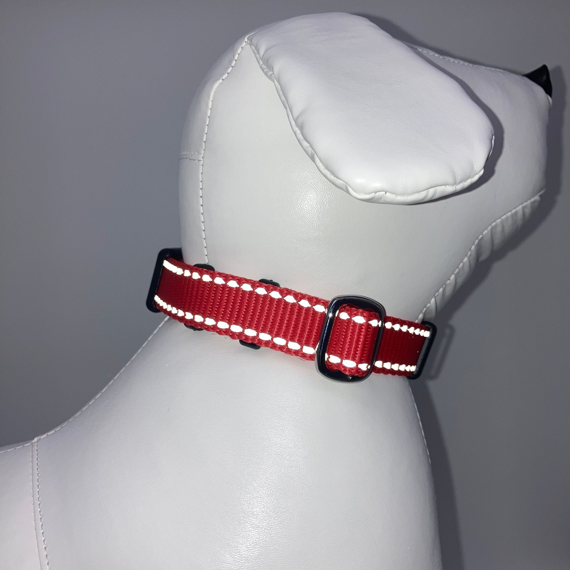 red collar with light reflecting stitches displayed on a stuffed toy (dog), showing the back of the head and the collar from behind