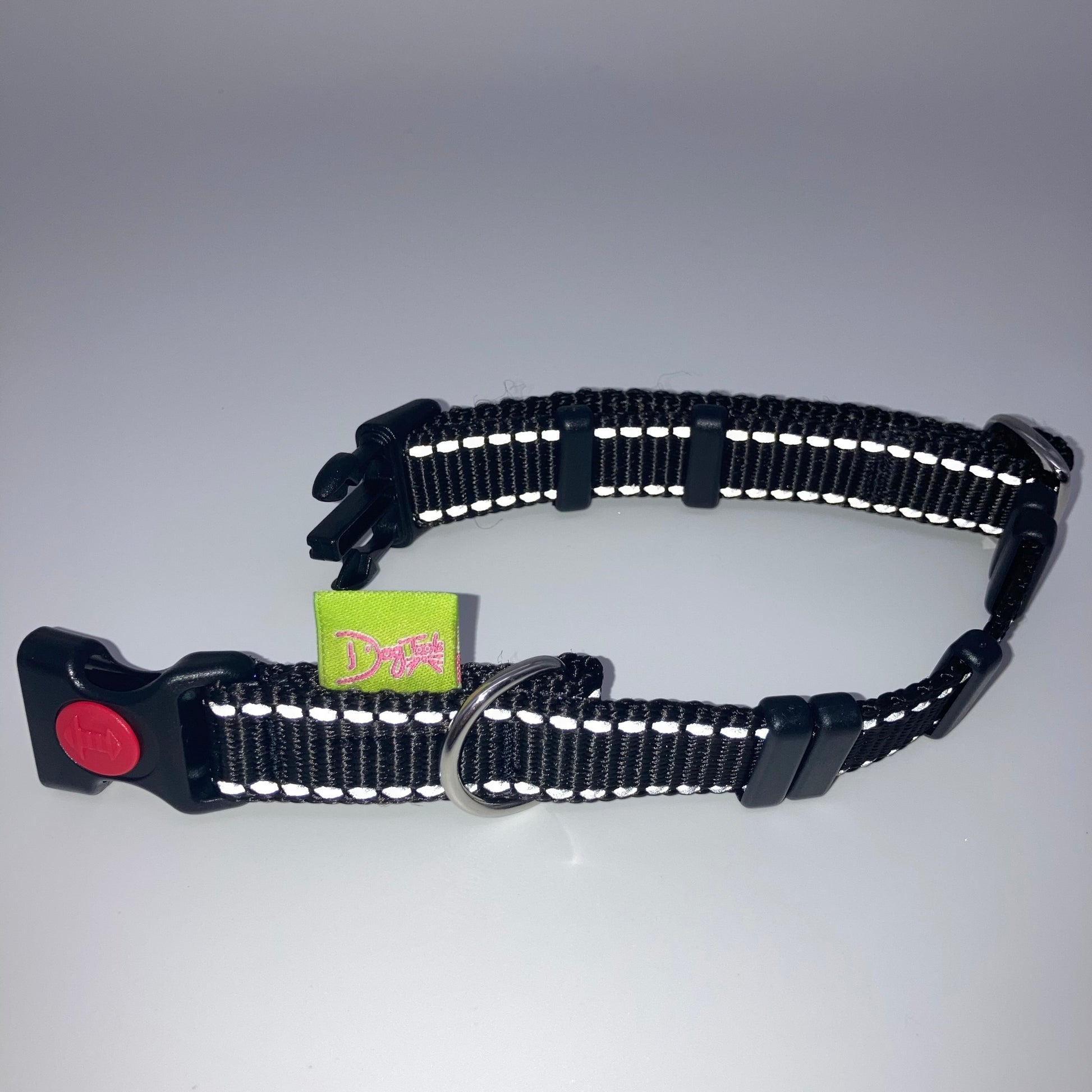 black collar with light reflecting stitches displayed on a white surface, unlocked, showing the black lock, stainless steel ring, the black loops and the applegreen DogTools label