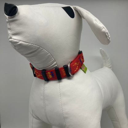 red Stitch (red fabric with print in 3 colors, yellow, orange and blue) collar displayed on a stuffed toy (dog), from the front of the dog, showing its head and torso