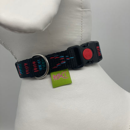 Stitch black (black fabric with print in 3 colors, red, light blue and green) collar showing the black lock, stainless steel ring and the applegreen label with DogTools logo on it. Displayed on a stuffed toy (dog), around the neck